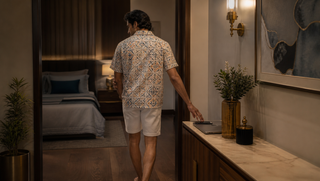 Synthetic Indian man in a white-cream geometric Sweet Dreams-style coord set placing his phone outside the bedroom, illustrating how a bed can learn the wrong signal.