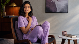 Synthetic Indian woman in orchid star Sweet Dreams-style pyjama set seated in a dawn reading corner, illustrating how bad dreams can make mornings feel unsettled.