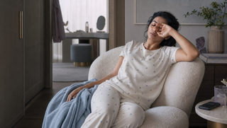 Synthetic South Asian woman in a swan-white star-print Sweet Dreams-style pyjama set resting in a dawn dressing alcove, illustrating why not to rush the last hour of sleep.