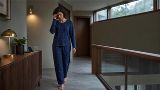 Synthetic woman in Sweet Dreams Celestial Night Pyjama Set walking through a sage and walnut hallway at dawn, illustrating sleep inertia after waking from deep sleep.