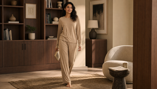 What is loungewear blog thumbnail: a synthetic South Asian woman in a soft beige Sweet Dreams lounge set walks toward camera through a walnut library-style living room.