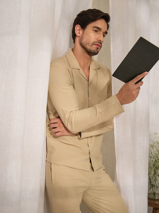 Men wearing a light brown textured pajama set, holding a book.
