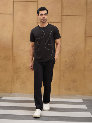 Men, standing, wearing a black t-shirt with white graphic print and black pants, compared to the previous image, the man is wearing a t-shirt and pants.