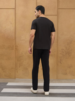 Men's black t-shirt and pants set, standing facing away from the camera.