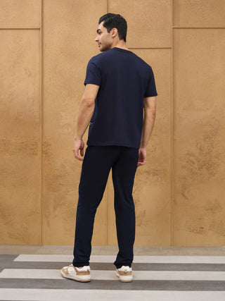 Men posing from behind in navy blue t-shirt and navy blue sleep pants with white and tan sneakers.