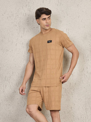Men's tan plaid t-shirt and shorts set, standing and posing with one hand in his shorts.