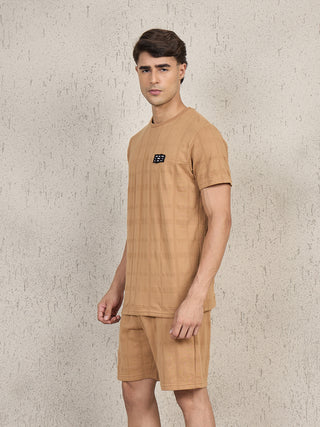 Men in a camel-colored, checkered t-shirt and shorts set, posed looking left.