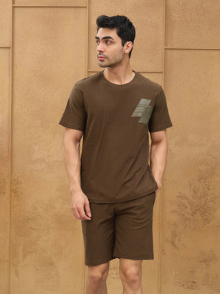 Men's brown patterned t-shirt and shorts set with a graphic detail on the chest, posed looking to the left.