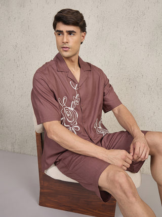 Men wearing a brown printed linen shirt and shorts set, sitting on a chair.
