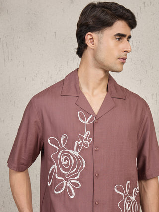 Men wearing a short-sleeved, mauve button-down shirt with white floral embroidery.