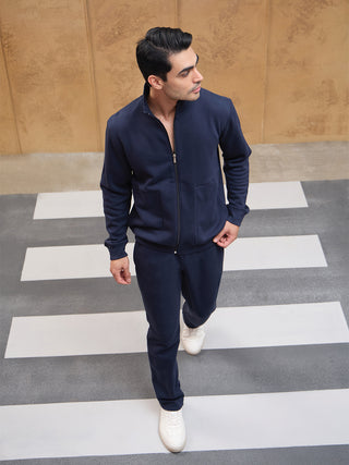 Men wearing a navy blue tracksuit with white sneakers walking on a crosswalk.