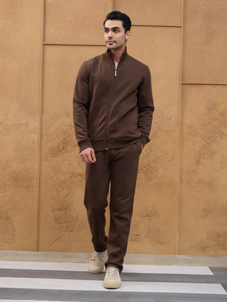 Men in a brown zippered sweatshirt and pants, standing and looking to the side.