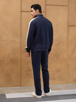 Men wearing a navy blue tracksuit with white accents, shown from the back.