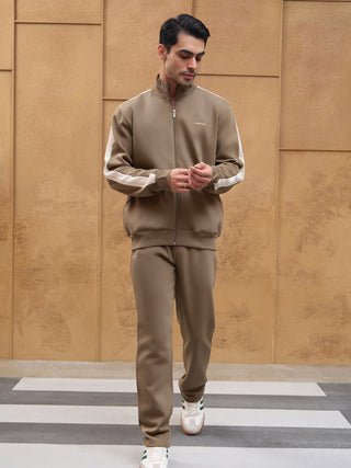 Men wearing a mocha brown track suit with white stripe accents on the sleeves.