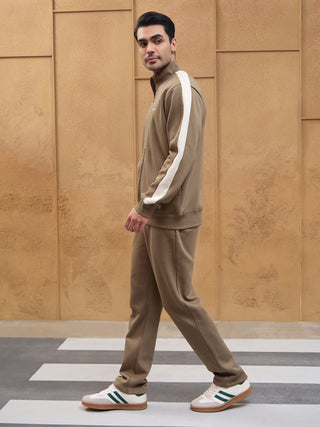 Men in a brown tracksuit with white stripes walking on a crosswalk.