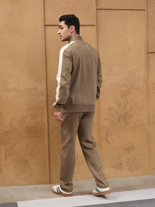 Men wearing a brown tracksuit with white stripe detailing on the sleeves.