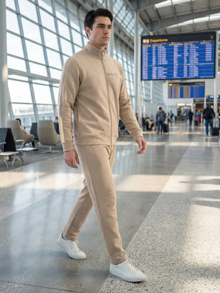 A man walks in a tan tracksuit with stripe detailing on the sleeves.