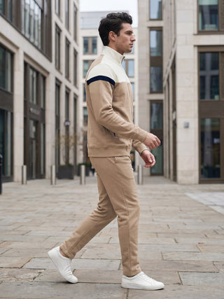 Men walking in a tan tracksuit with cream and navy accents.