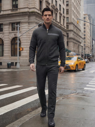 A man in a dark grey tracksuit walks confidently down a city street.