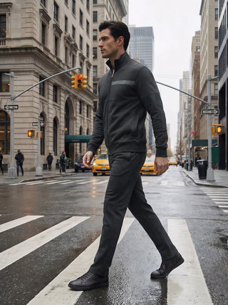 Men walking across a crosswalk in a charcoal gray zippered jacket and matching pants.