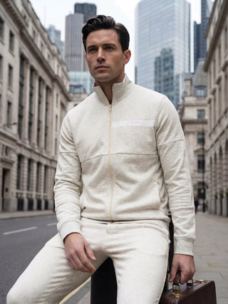 Men sitting with a light beige full-zip track jacket and matching pants.