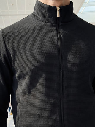 Men's black textured zip-up jacket with a stand-up collar, different from the previous image by the darker tone and ribbed texture.