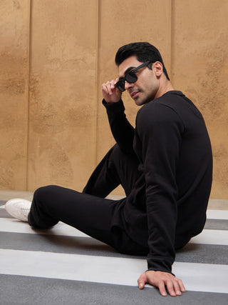 Men sitting in black solid color sweatshirt and pants.