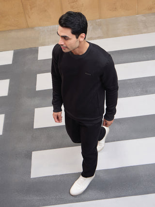 Men in a black loungewear set are walking across a crosswalk.