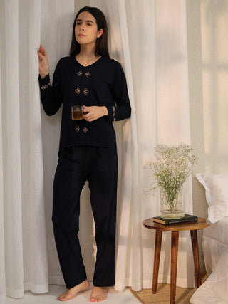 A woman wearing a navy blue pajama set with gold embroidery.