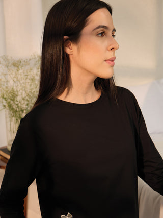 A woman in a black long-sleeved sleep shirt with a white floral print, shown from the chest up.