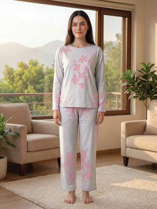 A woman in light gray pajamas with pink floral print stands facing forward.