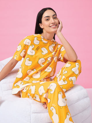 Women in a yellow pajama set with a duck print, sitting comfortably on a white plush chair.
