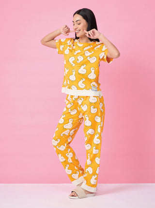 A woman in a yellow pajama set with a duck print, standing and posing playfully.