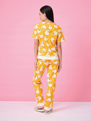 Woman wearing yellow pajama set with a duck print, posing from the back.