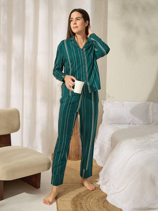 A woman in a green striped pajama set holds a mug in her hand.