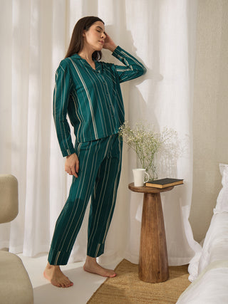 Woman in a teal green striped pajama set stands with her hand on her head.