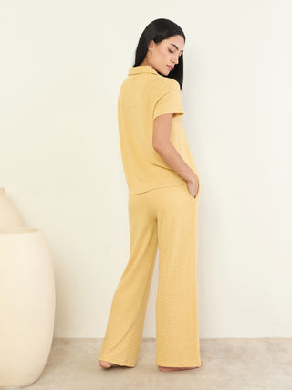 A woman in a yellow collared pajama set, standing with her back to the camera.