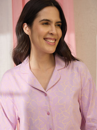 A woman poses in a light purple, floral print pajama top.