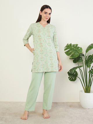 A woman is posing standing and wearing light green, printed sleepwear.