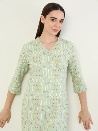 Women in a relaxed pose, wearing a light green, printed garment.