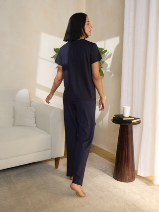 A woman in a navy blue sleepwear set poses from the back, facing away from the viewer.