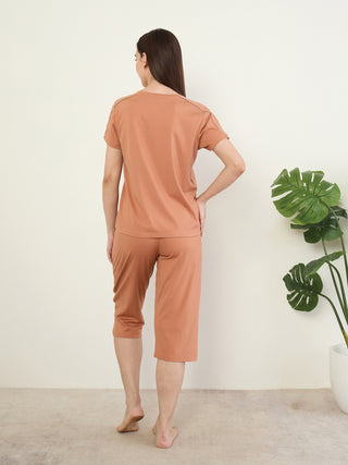 Women wearing a rust-colored short-sleeved t-shirt and capri pants set, standing with their back to the camera.