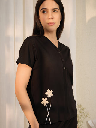 Women's black short-sleeve sleepshirt with embroidered flowers and a v-neckline.