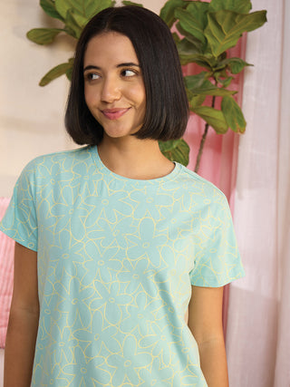 Women wearing a light blue t-shirt with a yellow floral print, looking to the side.