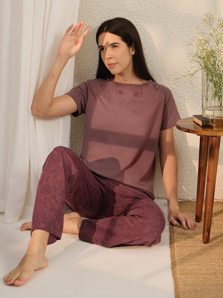 Woman in mauve floral print pajamas sitting on the floor.