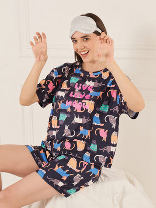 Women in a navy blue sleepwear set with a repeating cat print, smiling and posing in front of a white background.