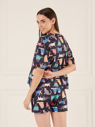 A woman models a navy blue pajama set with a playful cat print.