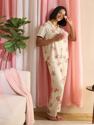Women's yellow gingham pajama set with pink teddy bear print, the model is standing and holding a bowl of candies.