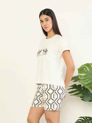 A woman poses in a cream-colored t-shirt with a camel print and matching printed shorts.