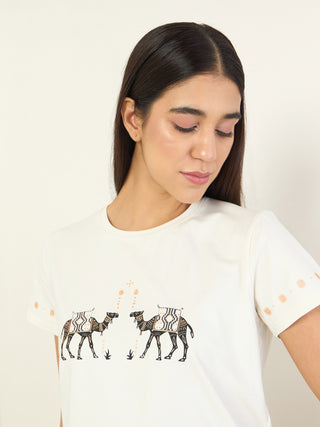 A woman is shown from the chest up, wearing a white t-shirt with a camel print.
